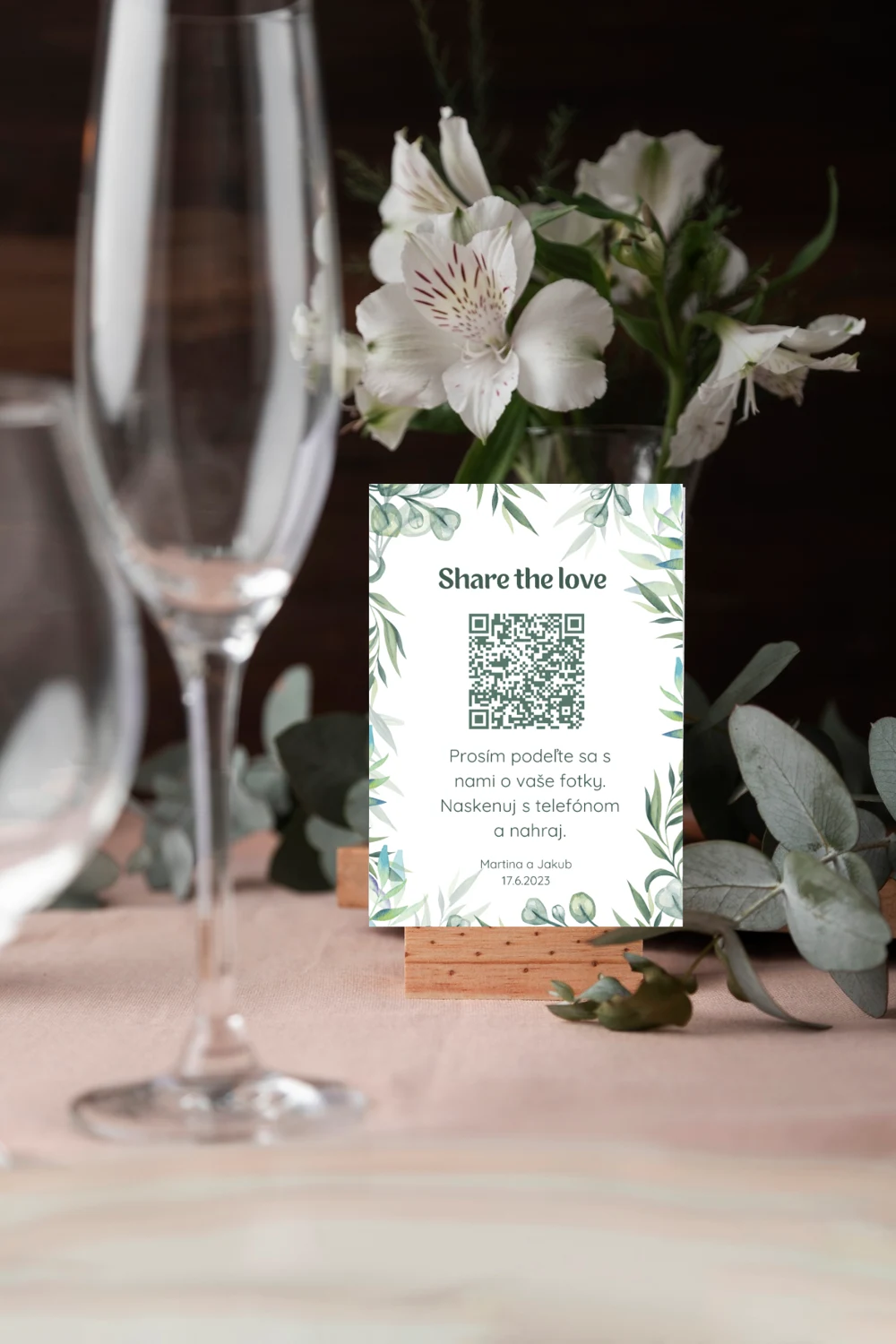 Svatební kartička s QR kódem na stole mezi květinami a skleničkami